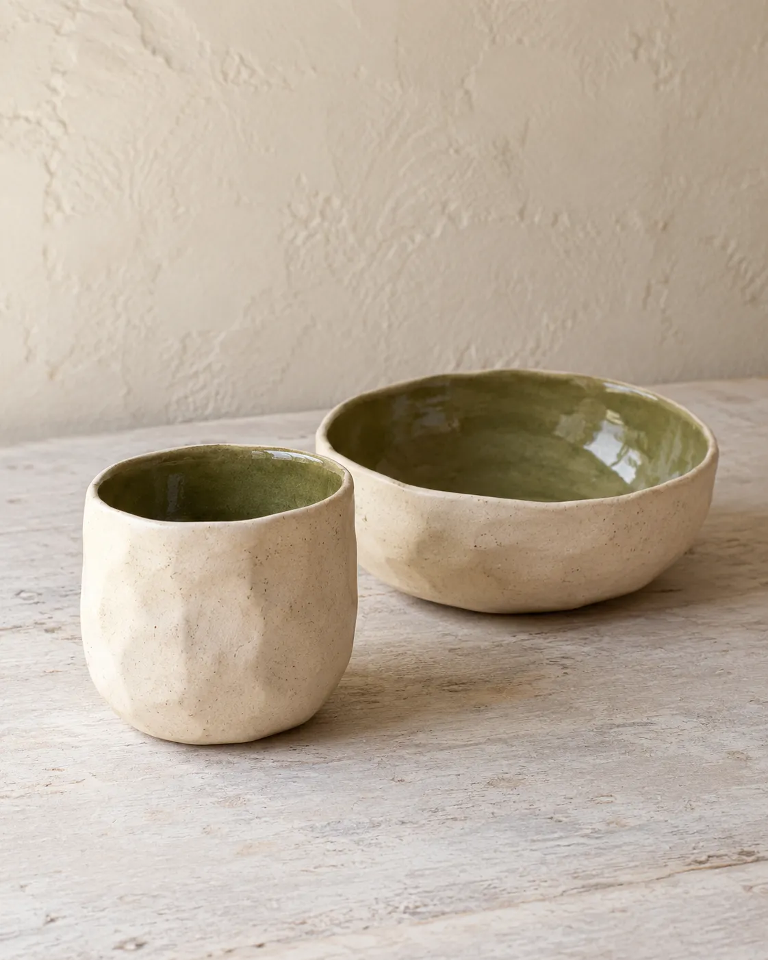 A faceted cream cup and matching bowl, both glazed green inside