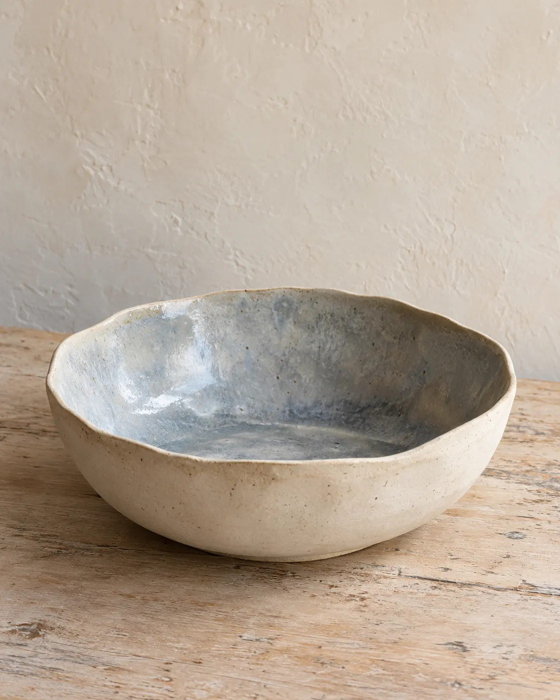 A wide hand-built bowl, cream on the outside and blue-grey glaze inside